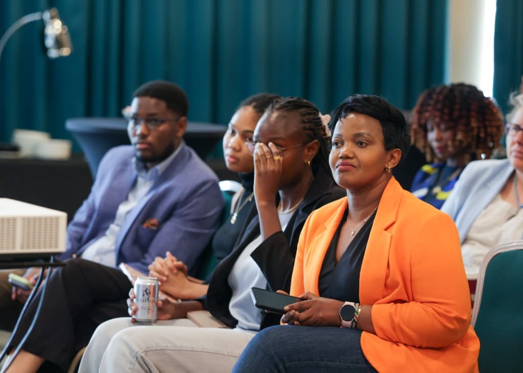 Attendees seated at a Qhala Trust convening, including a woman in an orange blazer