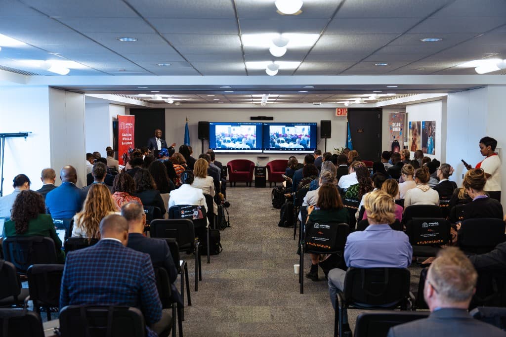 Full conference hall with a speaker at the podium and Africa n' AI branding during a convening